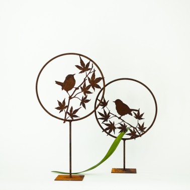 Uccellino in metallo arrugginito su ramo con piedistallo